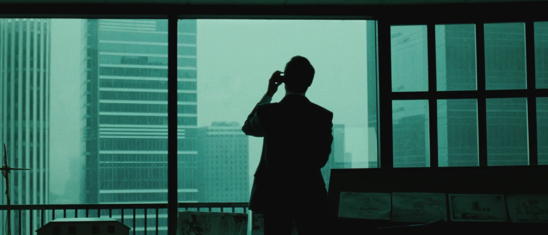 Consultant silhouetted at an office window above the city