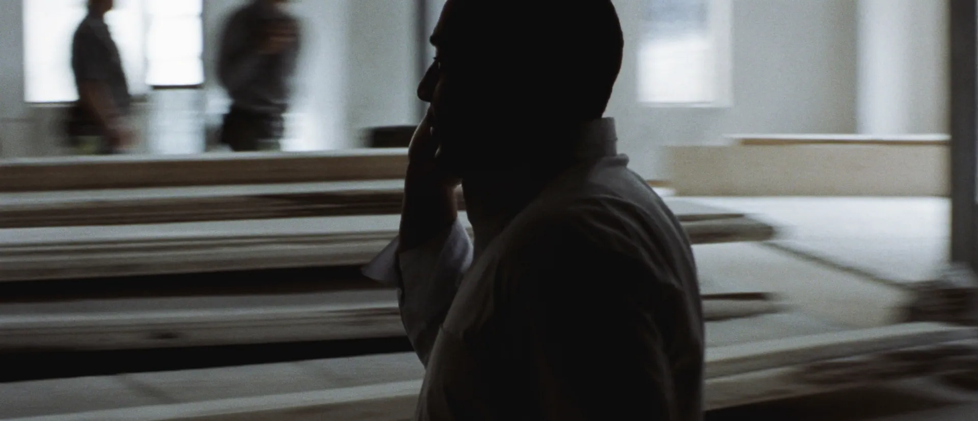 Silhouetted project manager on the phone beside stacked plasterboard