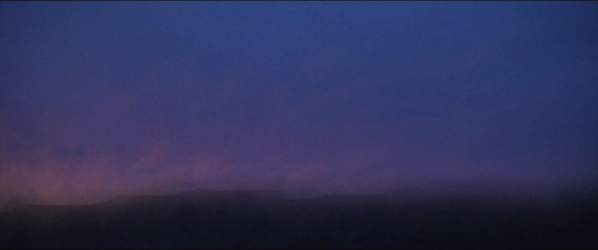Dawn sky streaked into soft blue and violet bands over a dark horizon