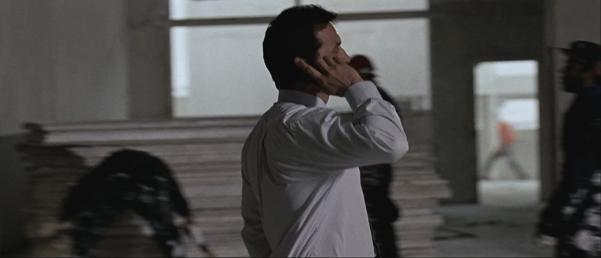 Project manager on the phone walking a fit-out floor, seen from behind, trades blurred around him