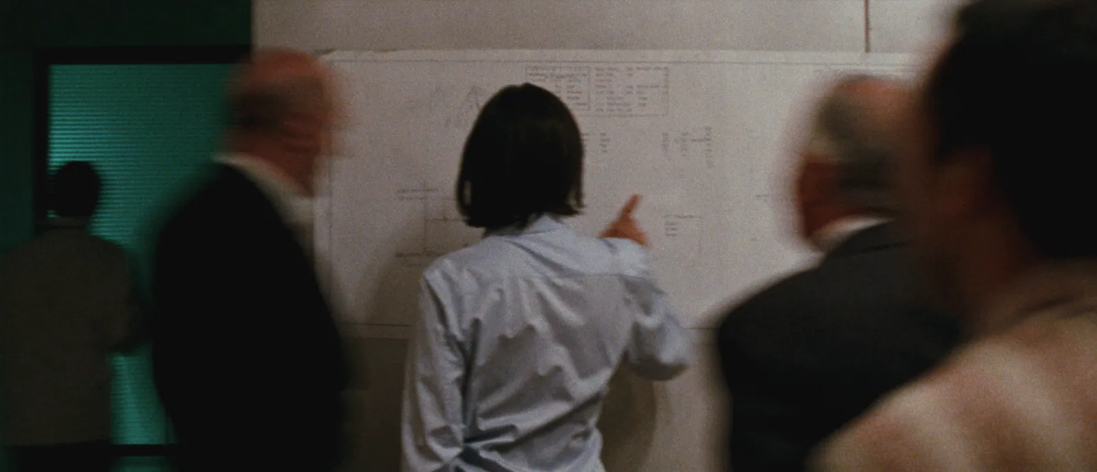 Builder walking through a site office, back to camera, drawings on the wall